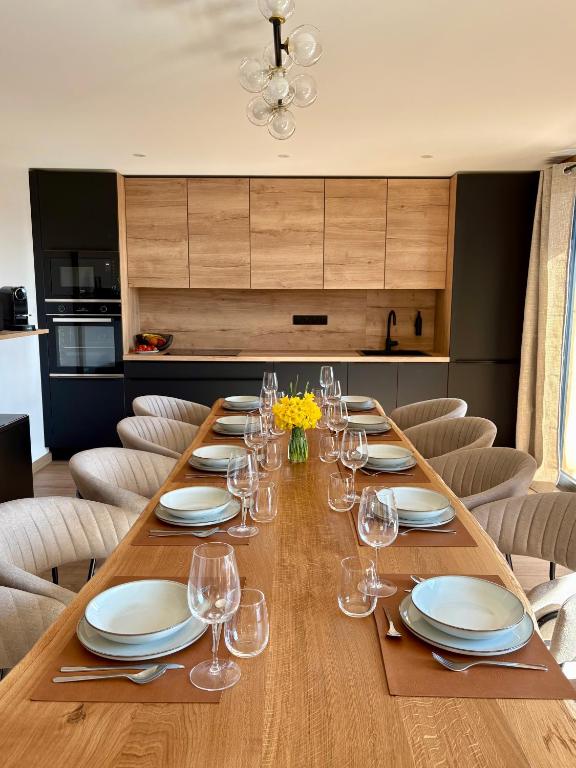- une longue table en bois avec des assiettes et des verres à vin dans l'établissement Chalet Cimebleu SPA & Sauna, à Basse-sur-le-Rupt