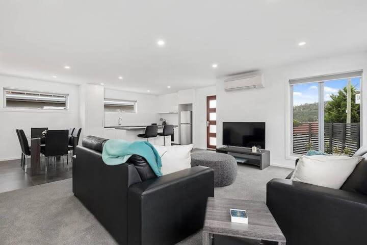 a living room with a black couch and a table at The Villa at 165 Contemporary apartment in Warrane