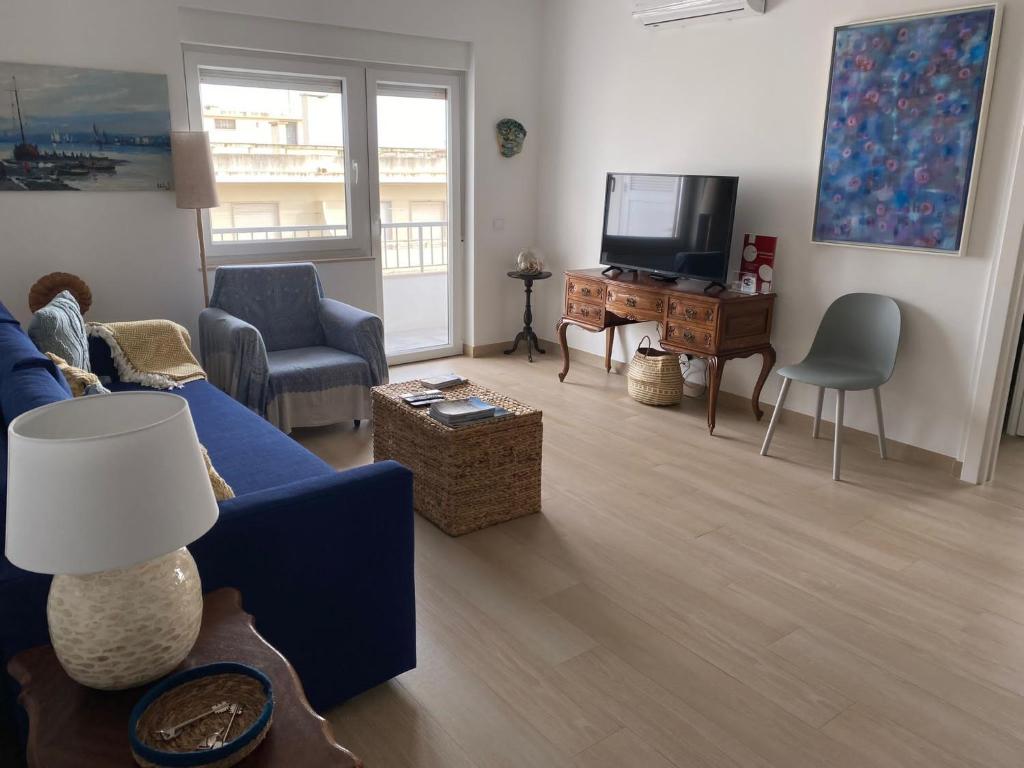 a living room with a blue couch and a tv at Casa dos Búzios - 1-bedroom apartment with sea view in Armação de Pêra