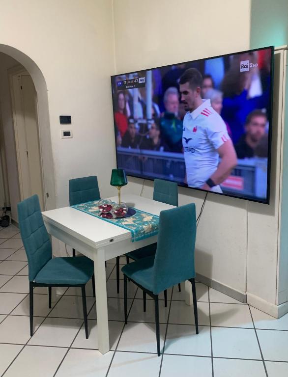a white table with chairs and a tv on a wall at Appartamento ANGIE in Forio d'Ischia