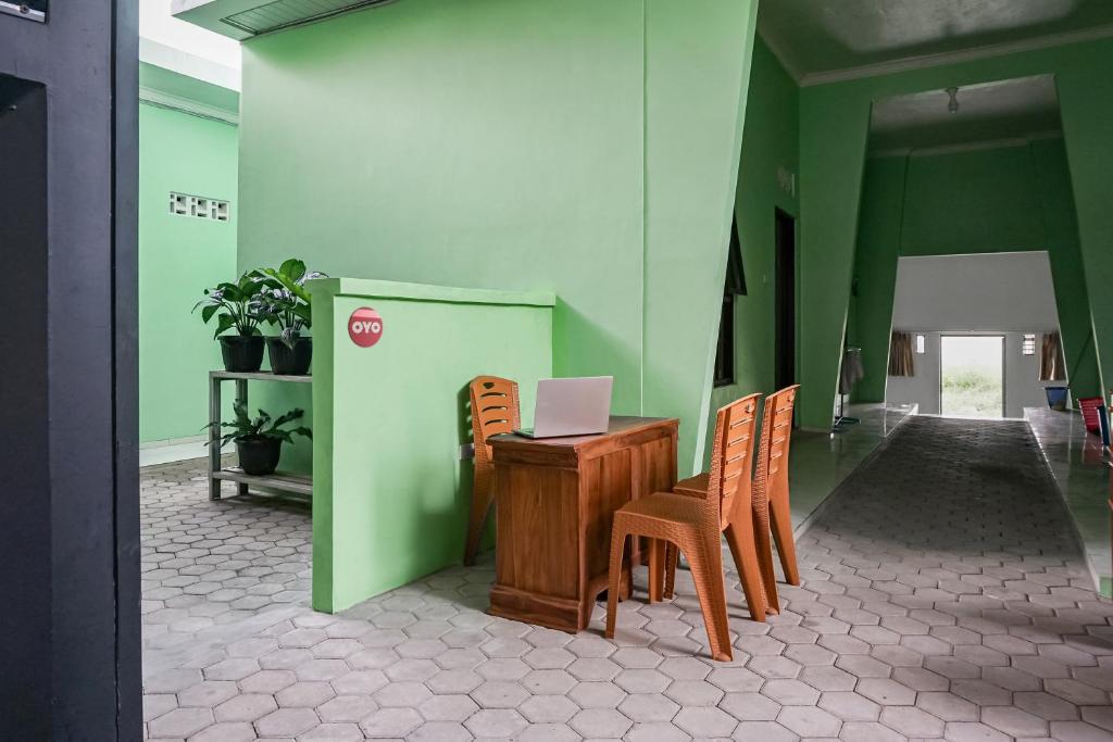 班达楠榜OYO 93695 Guest House Riharti Syariah的客房配有书桌、椅子和笔记本电脑