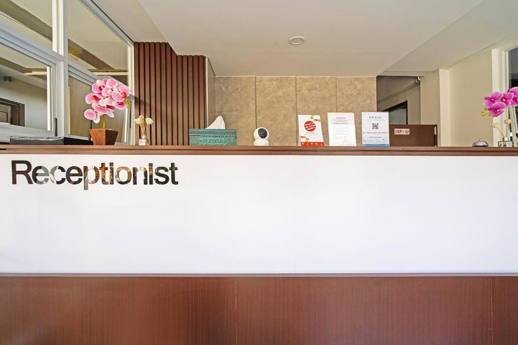 a reception desk in a hotel lobby with a receptionist sign at Capital O 1898 Louise Place in Cianjur