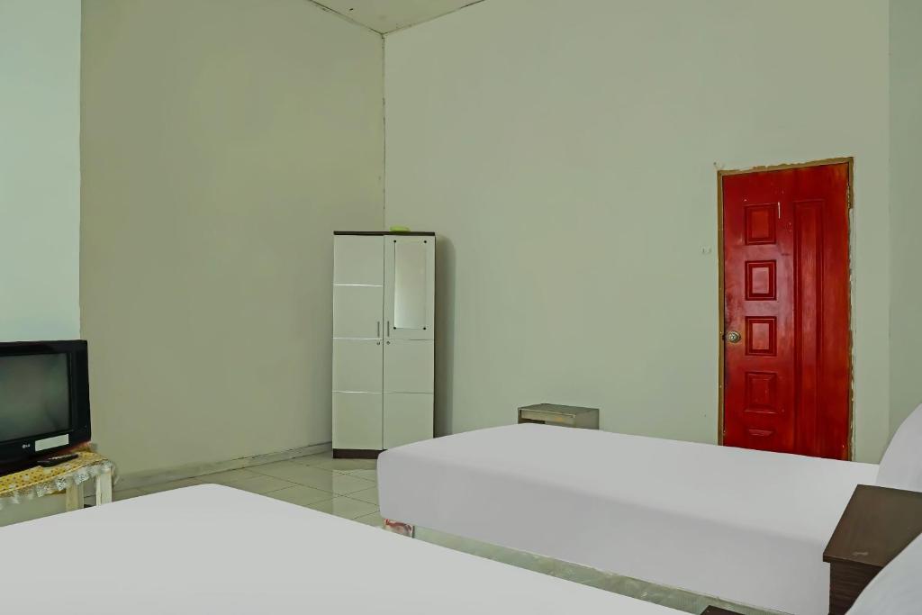 Habitación con 2 camas y puerta roja en Hotel O Wilma Kost Syariah, en Banjarmasin