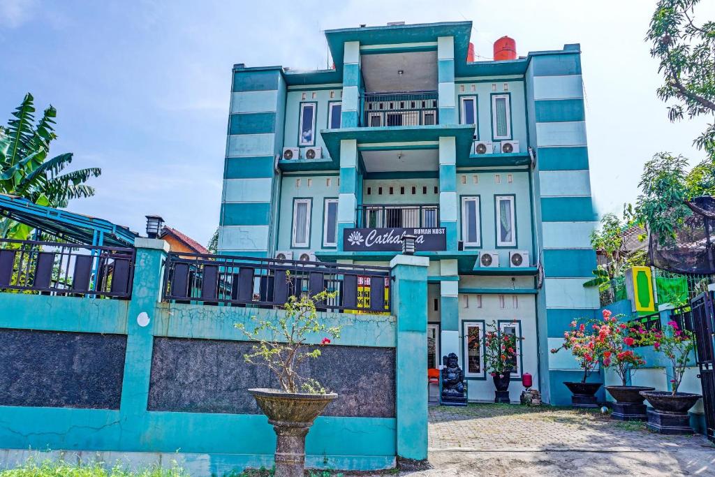 a blue building with a tree in front of it at Hotel O Home Stay Elis Cateliya Syariah in Karawang