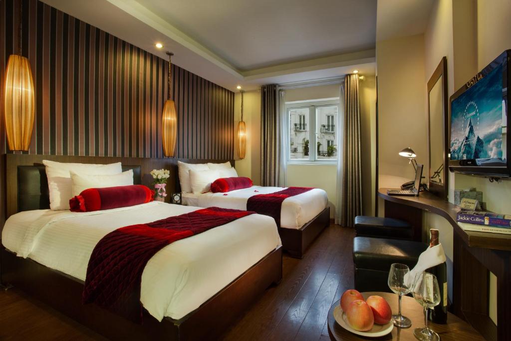 a hotel room with two beds and a couch at Golden Art Hotel in Hanoi