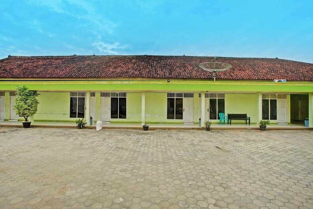 a large yellow building with a red roof at Hotel O Sejahtera Syariah in Umbulan Tulungmeris