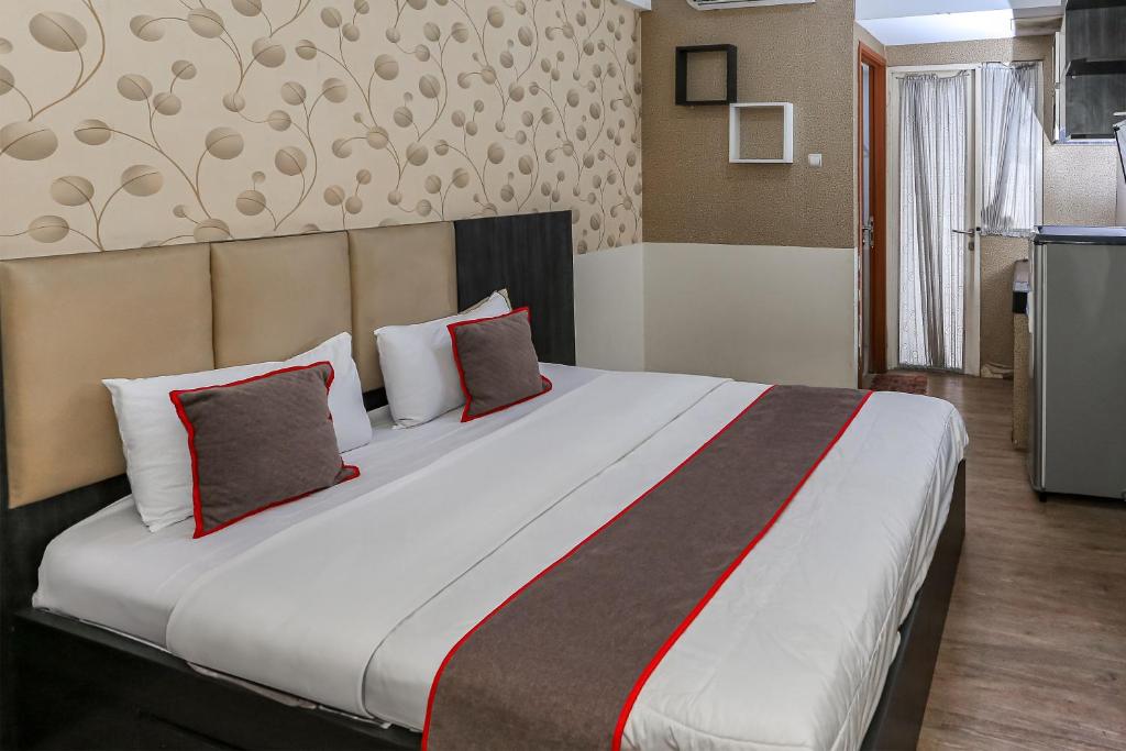 a bedroom with a large white bed with red pillows at Capital O 93372 Aurora Residence in Tangerang