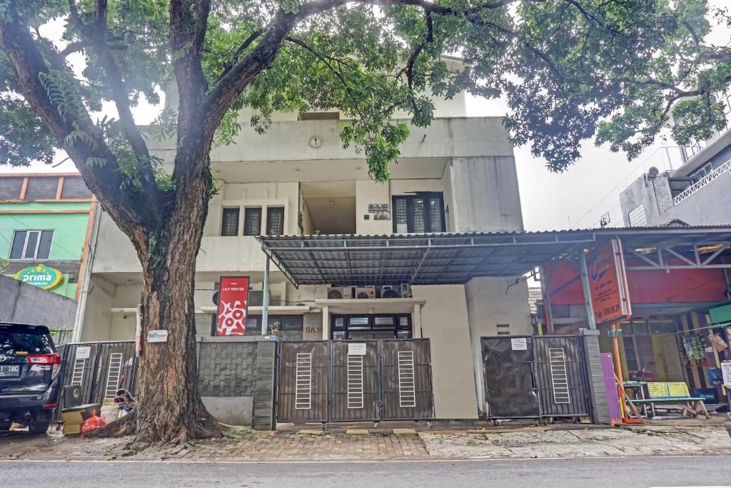 a building with a tree in front of it at Hotel O Lily House in Tangerang