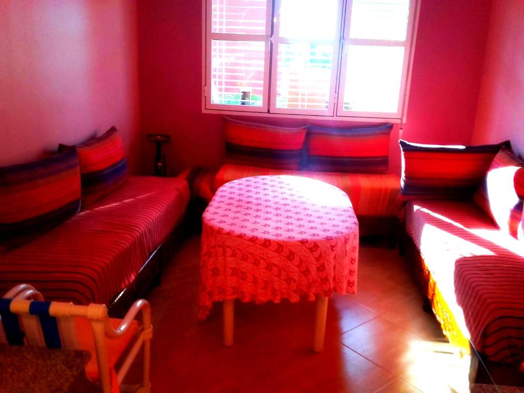 Camera rossa con tavolo, sedie e finestra di Maison de Vacances a Saïdia