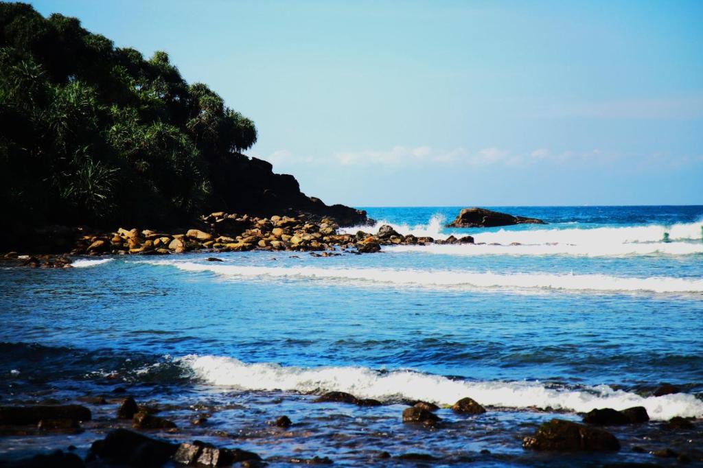 a beach with a bunch of rocks and the ocean at Dilmalee Village in Dickwella