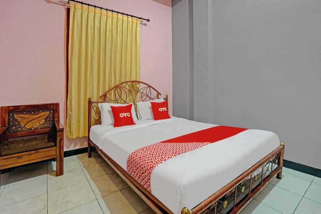 a bedroom with a bed with red pillows and a window at Hotel O Harwin Homestay in Batu
