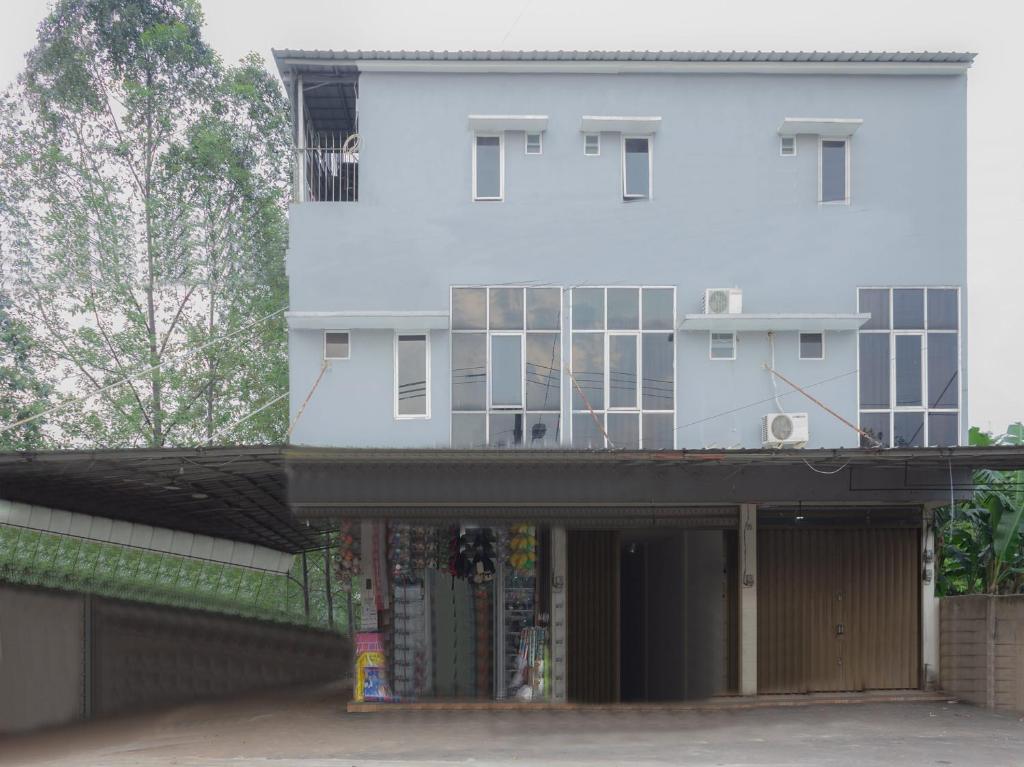 a white building with a balcony on top of it at Hotel O 77 Guesthouse in Tjilandak