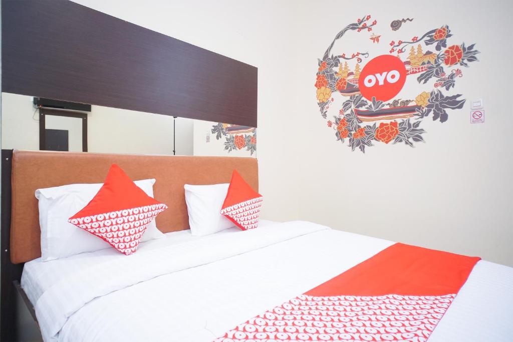 a bedroom with a bed with red and white pillows at Hotel O near Universitas Widya Dharma formerly Nugraha Residence in Talang Kelapa