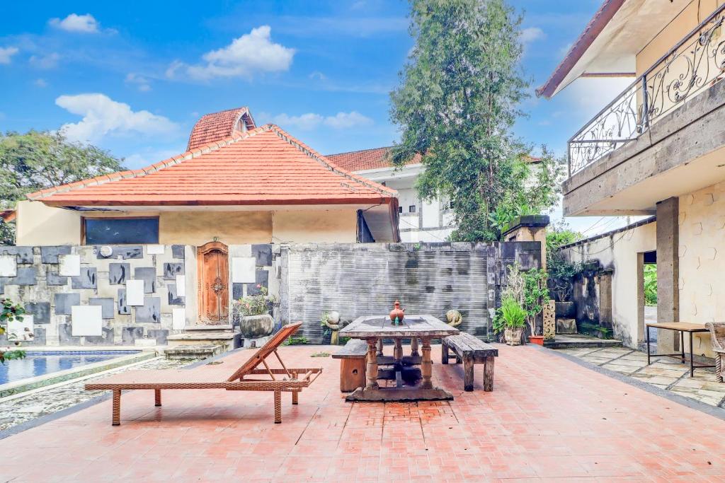 a patio with a table and benches in front of a building at Collection O Putri Inn Homestay in Sanur