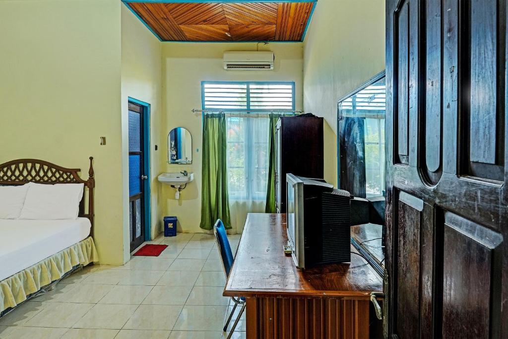 a bedroom with a bed and a desk with a television at Capital O 91806 Hotel Batu Suli in Palangkaraya