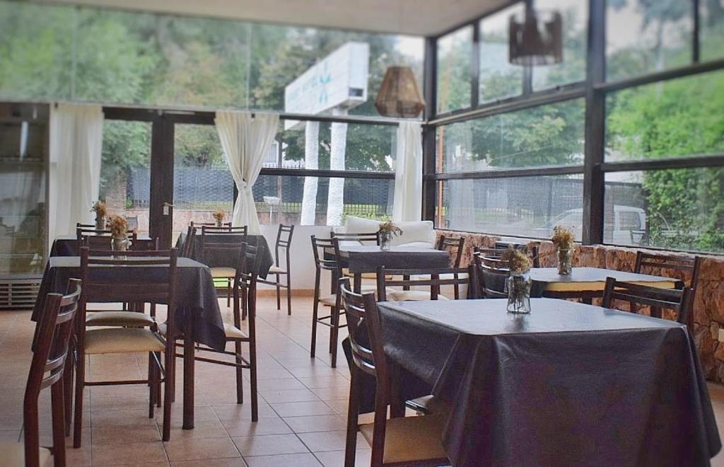 a restaurant with tables and chairs and windows at Apart Hotel El Molino de la Costa in Villa Carlos Paz