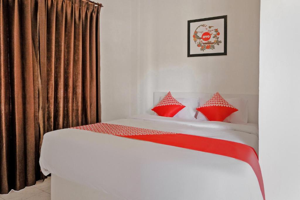 a bedroom with a bed with red pillows at Hotel O Kina Family Residence Syariah in Malang