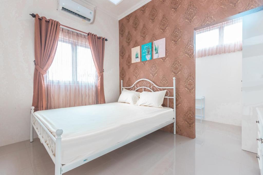 a white bed in a room with a window at OYO Life 2658 Kost Rasyamada in Bogor