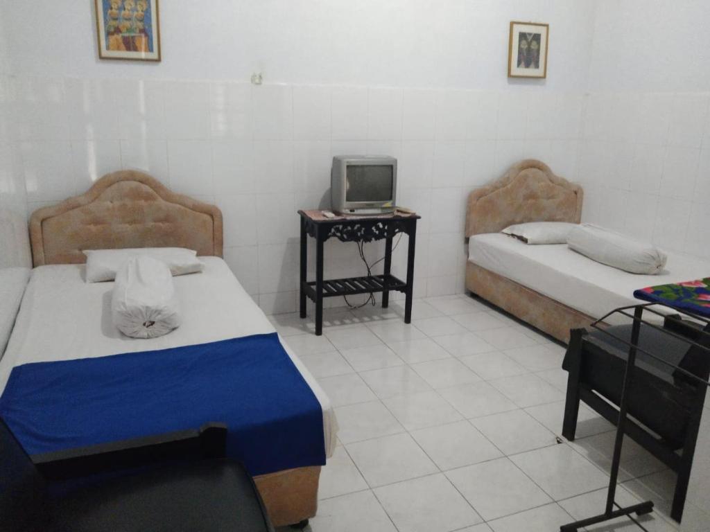 a bedroom with two beds and a tv on a table at EXPRESS O 91176 Hotel Puri Gandaria in Parepare