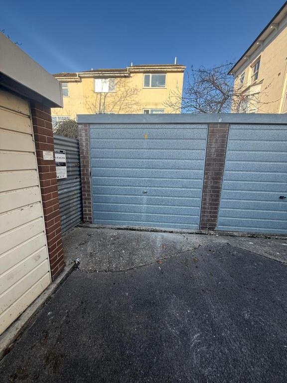 a garage with a blue garage door next to a building at Bright and Spacious 2BR Maisonette Sleeps 8, Game Room, 5 mins to Brighton Beach and City Centre in Brighton & Hove