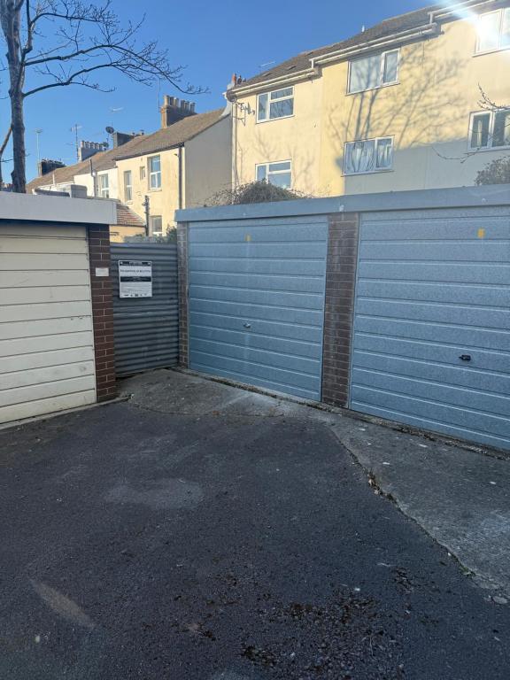 a garage with a blue gate and a building at Bright and Spacious 2BR Maisonette Sleeps 8, Game Room, 5 mins to Brighton Beach and City Centre in Brighton & Hove