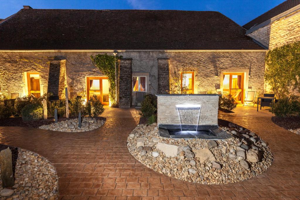 a stone house with a fountain in a courtyard at Hotel De La Cloche in Beaune