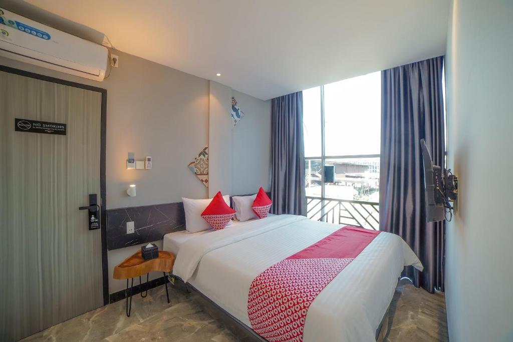 a bedroom with a bed with red pillows and a balcony at Capital O 90447 Kardopa Hotel Megapark in Medan