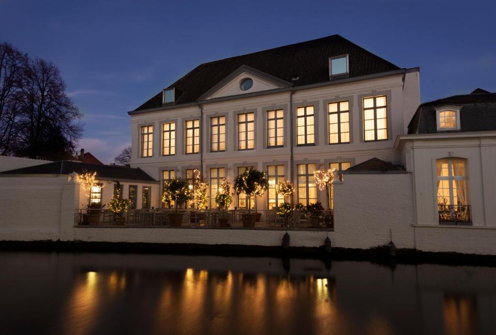 a large house with lights on the water at night at Hotel Van Cleef in Bruges