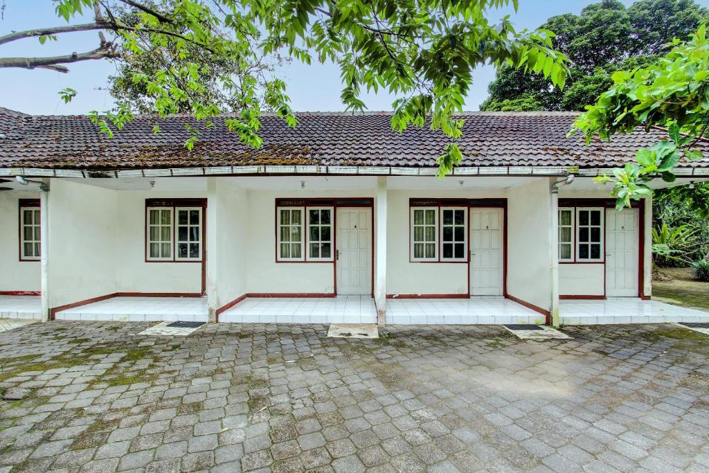 a white house with red doors and a courtyard at Hotel O Asta Guesthouse in Yogyakarta