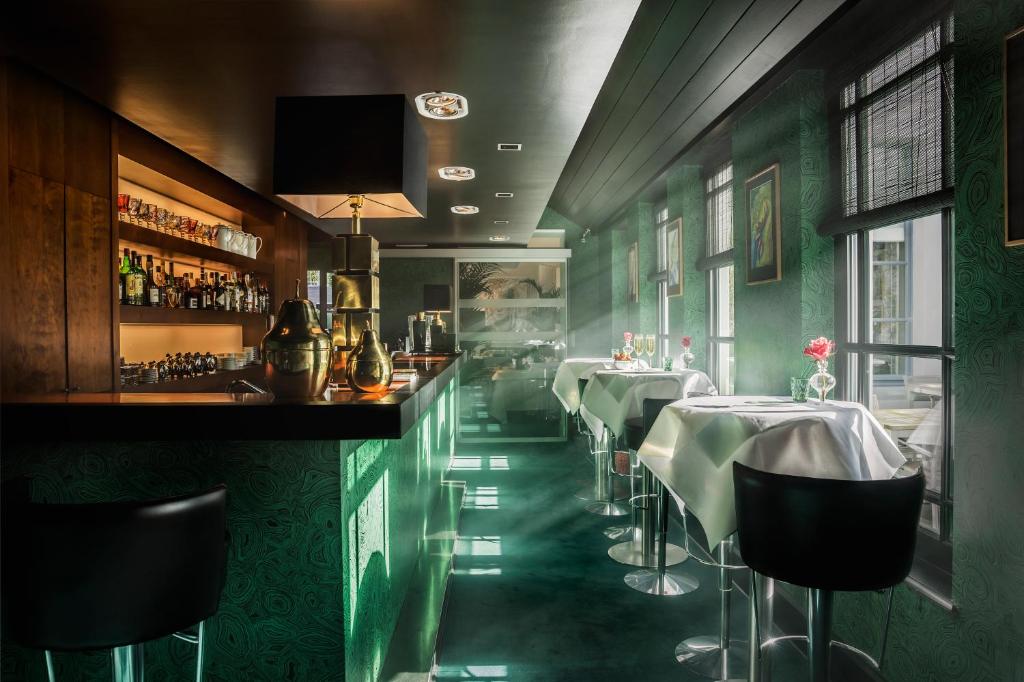 a restaurant with green walls and a bar with tables at Hotel Van Cleef in Bruges