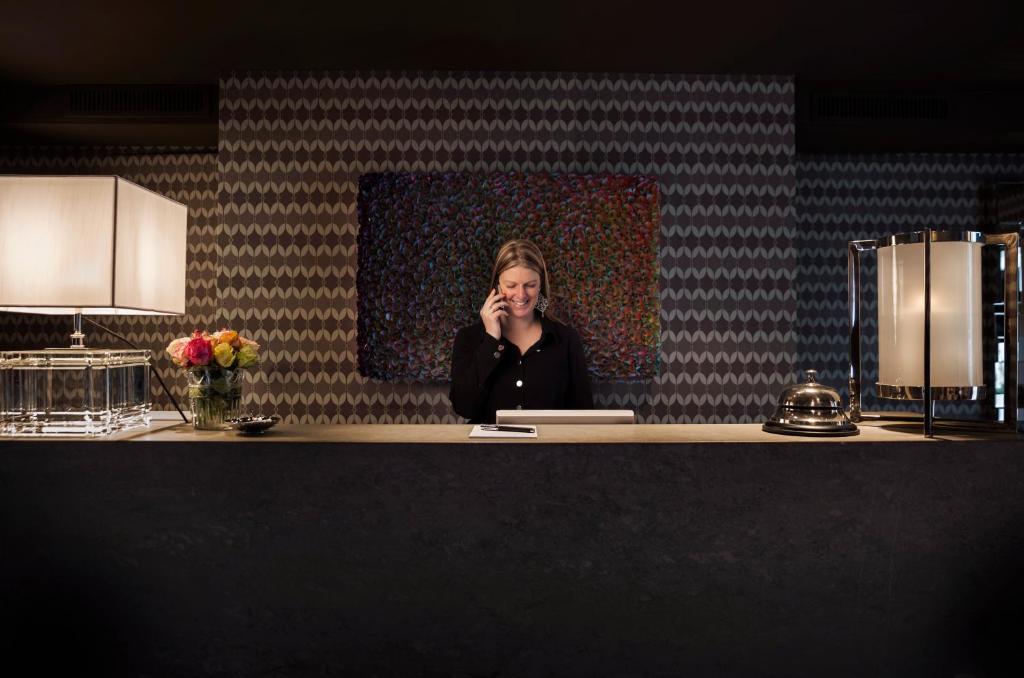 a woman sitting at a counter talking on a cell phone at Hotel Van Cleef in Bruges