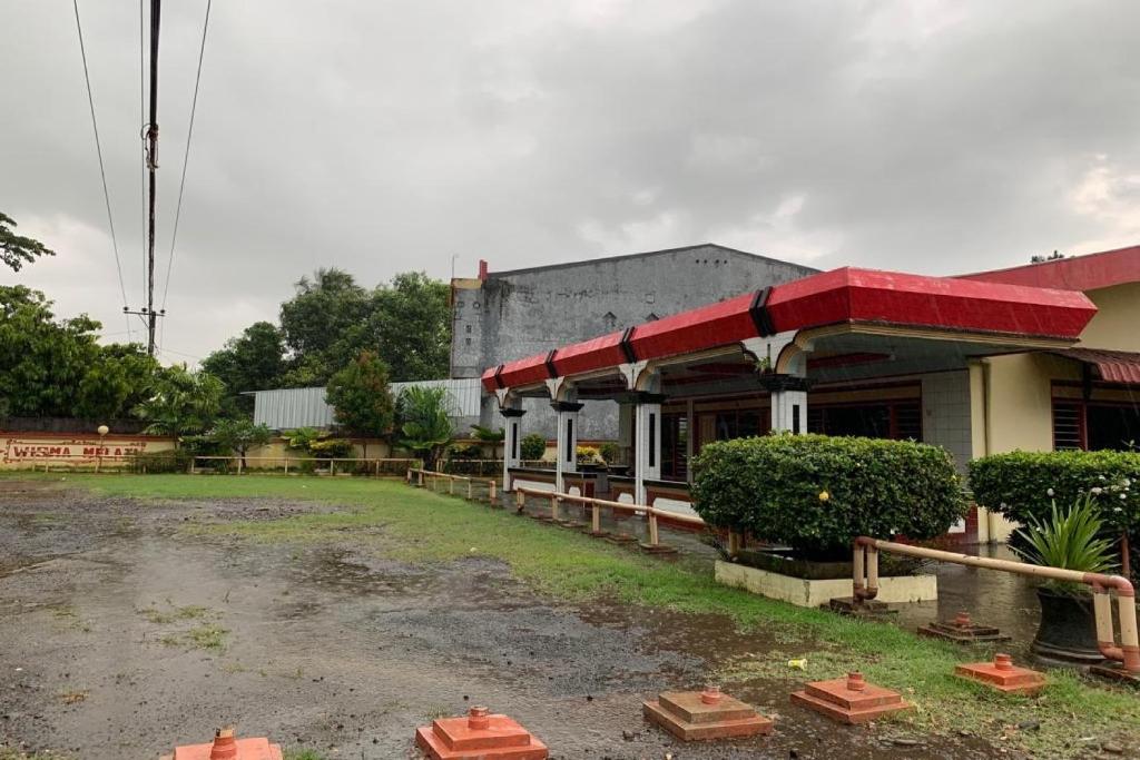 a building with a red awning next to a parking lot at Hotel O Wisma Rima Melati in Tolo