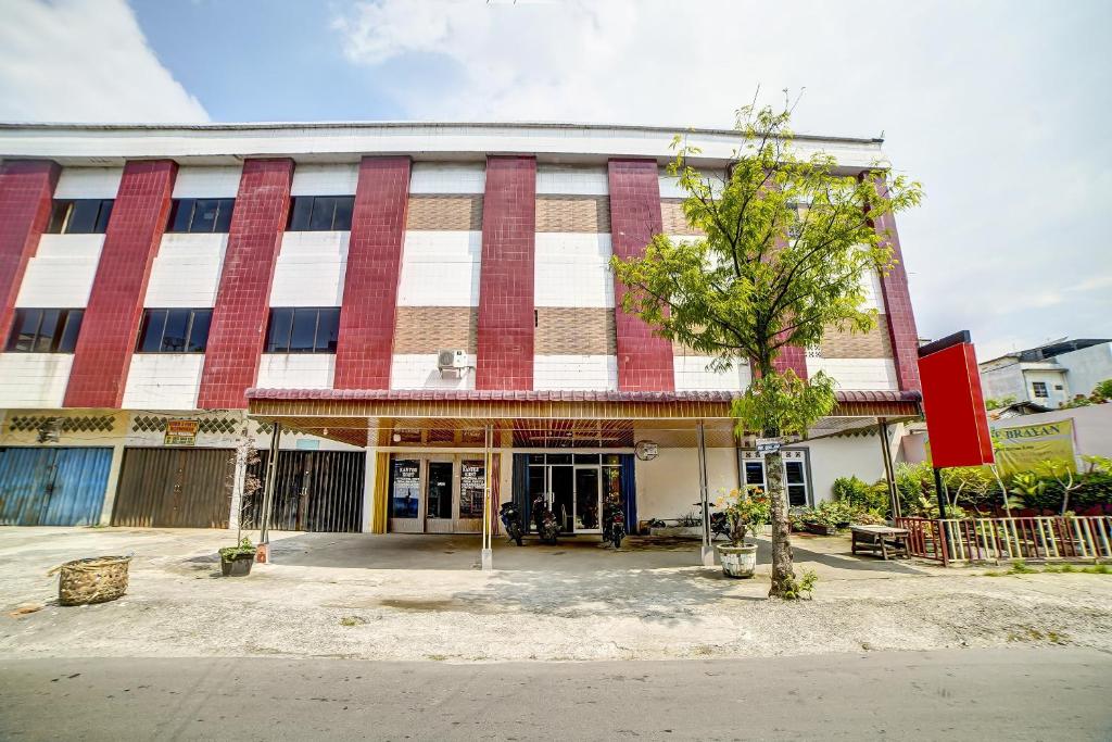 a building with a tree in front of it at Hotel O near Citraland formerly Brayan Guest House in Medan