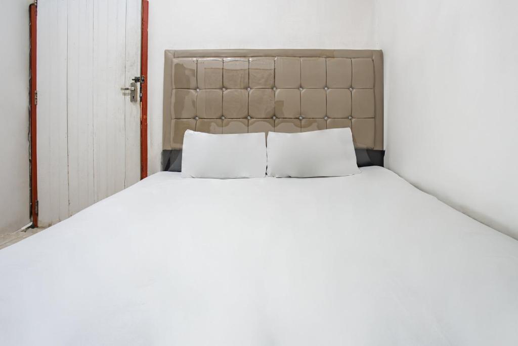 - un lit blanc avec deux oreillers dans l'établissement Hotel O Penginapan Tulimario Syariah, à Jambi