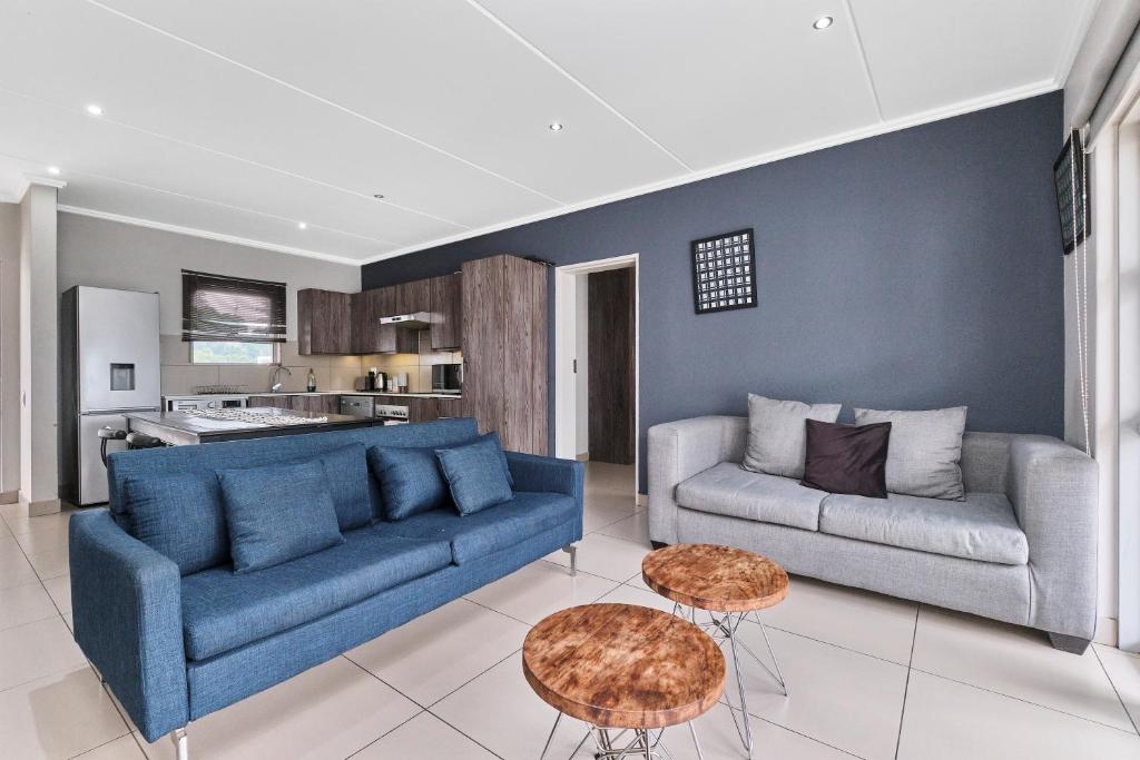 un salon avec un canapé bleu et une cuisine dans l'établissement Spacious 2BR Apt Minutes from Sandton City with Gym and Pool, à Johannesbourg