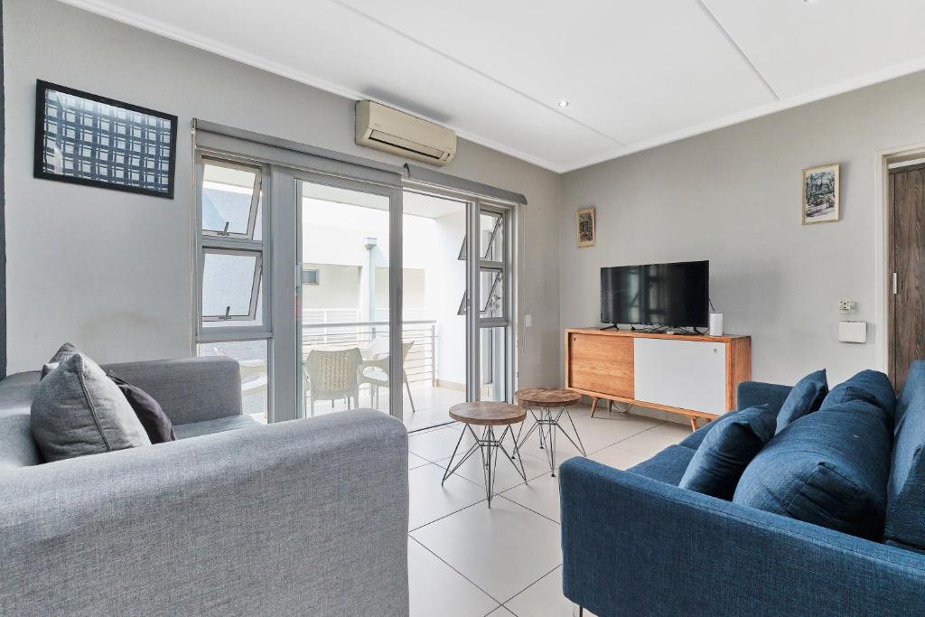 ein Wohnzimmer mit 2 blauen Sofas und einem TV in der Unterkunft Modern Comfort Retreat in Central Sandton with WiFi , Gym and Pool in Johannesburg