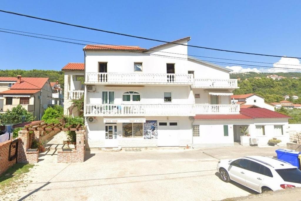 a white house with a car parked in front of it at Apartments with parking space Palit, Rab - 23622 in Rab