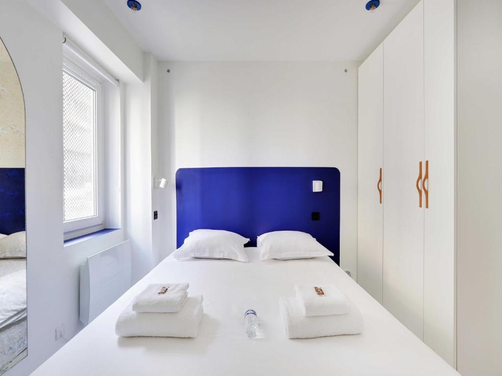 une chambre blanche avec une tête de lit bleue et un lit dans l'établissement Authentic apartment - 1BR 2P - Goutte-d'Or, à Paris