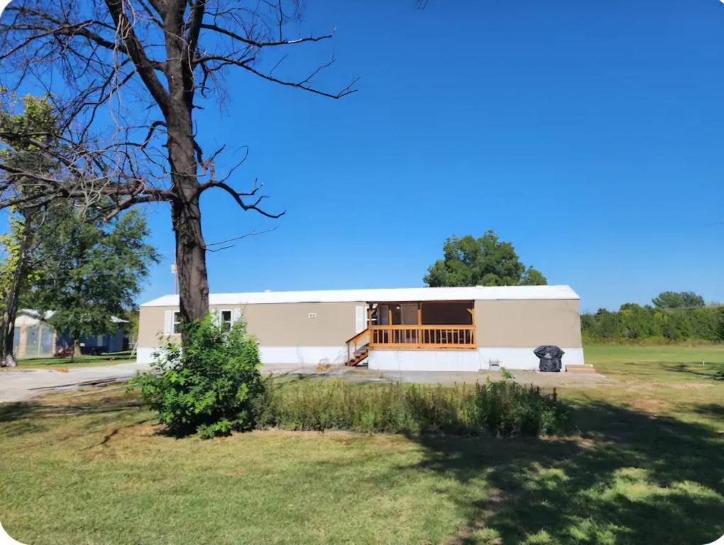 a white building with a tree in the foreground at Pop's Place -Lakeview 3bd 2 ba on 6 acres in Fort Gibson