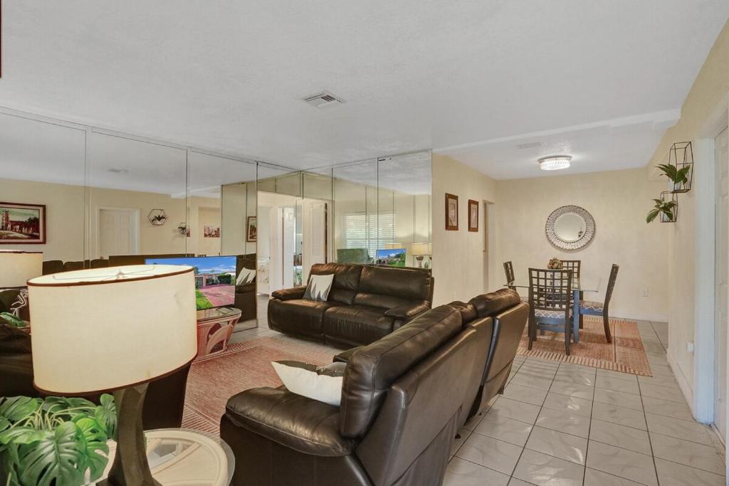 Una sala de estar con un sofá de cuero y una mesa. en Cozy Miami 2Bd Bungalow, en Biscayne Gardens