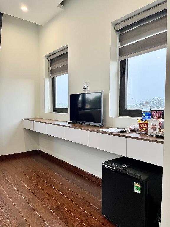 a living room with a television and two windows at SAFFRON Dalat in Da Lat