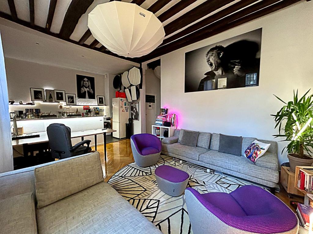 un salon avec un canapé et des chaises violettes dans l'établissement Fantastique et Incroyable appartement Le Marais Paris, à Paris