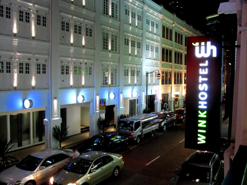a lit up building with cars parked in front of it at Wink at Mosque Street in Singapore