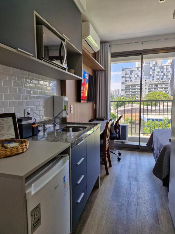 Hotel Studio Metro Alto da Boa Vista, a kitchen with a sink and a room with a bed at Studio Metro Alto da Boa Vista in São Paulo