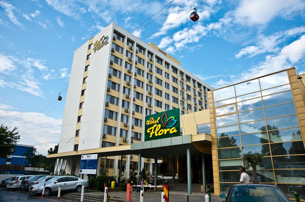 a large hotel building with a kite in the sky at Hotel Flora in Mamaia