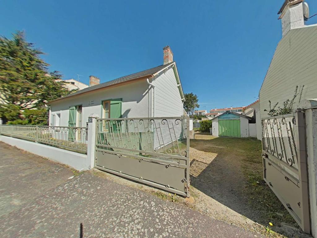 une maison blanche avec une porte en face dans l'établissement Maison de Vacances 2 Pièces à 100m Plage - Saint-Jean-de-Monts - FR-1-224C-343, à Saint-Jean-de-Monts