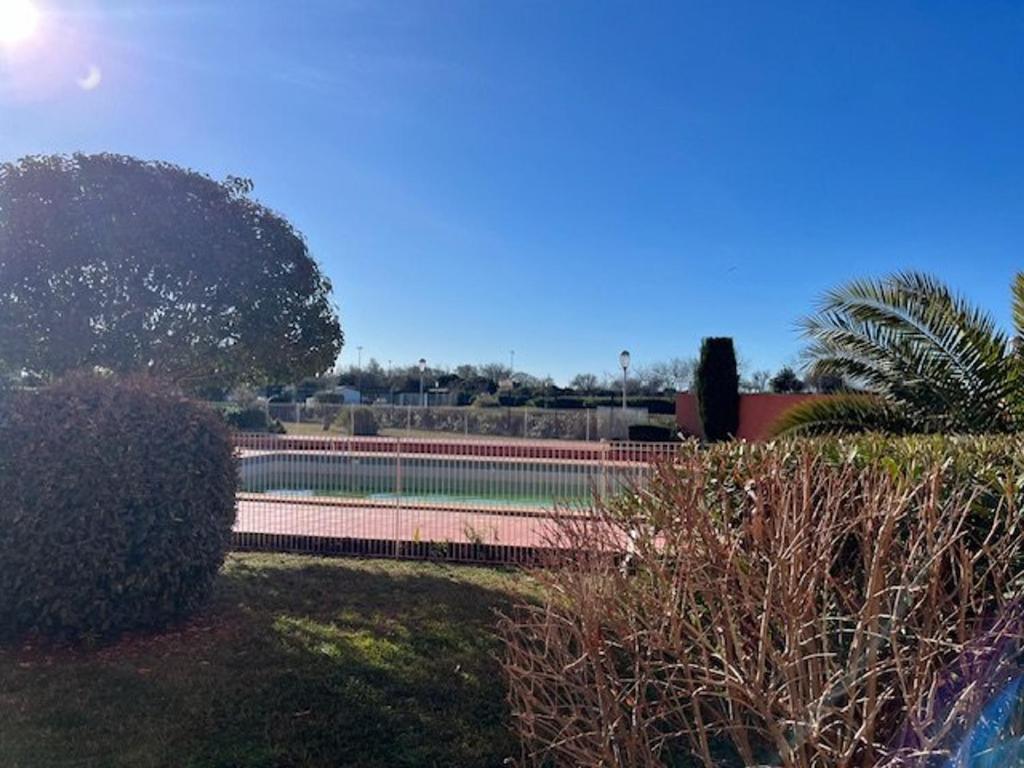 - un court de tennis dans un parc planté d'arbres et de buissons dans l'établissement Appart rez de chaussée avec terrasse, proche plage, parking - FR-1-749-93, au Cap d'Agde