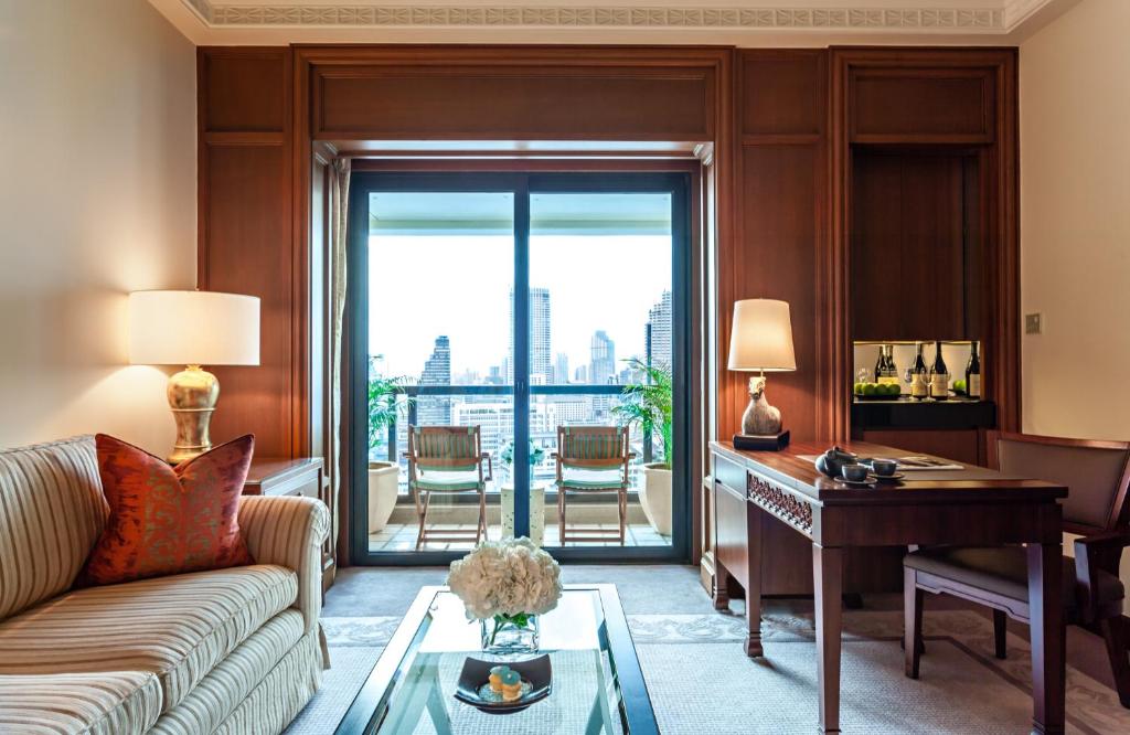 a living room with a couch and a desk at The Peninsula Bangkok in Bangkok