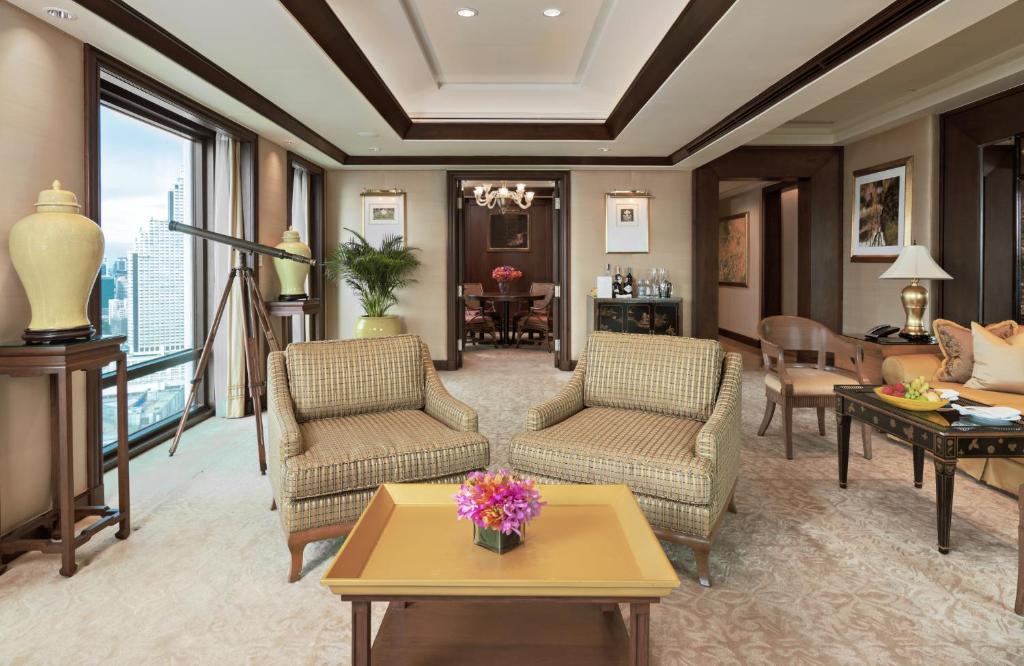 a living room with furniture and a large window at The Peninsula Bangkok in Bangkok