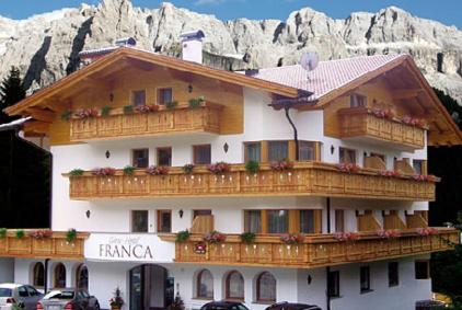 a large building with wooden balconies in front of a mountain at Garni Hotel Franca b&b in Selva di Val Gardena